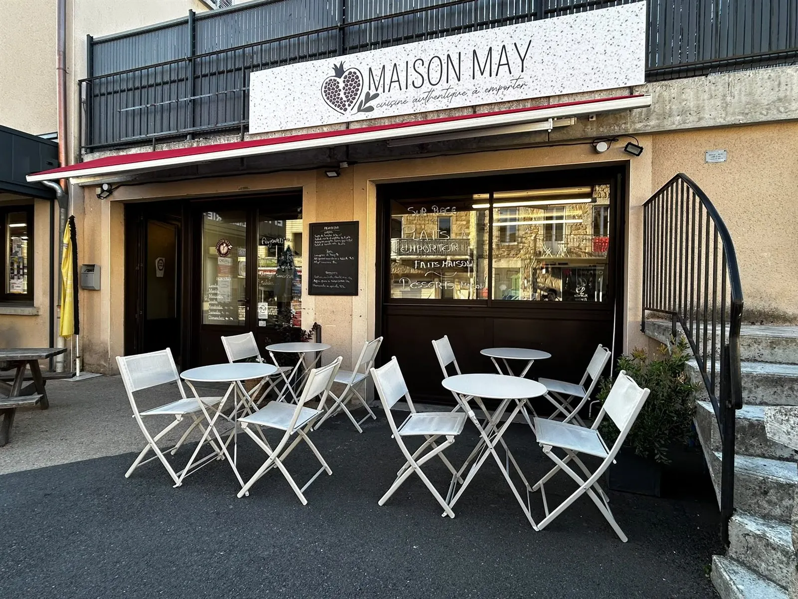 La devanture de Maison May à Aumont-Aubrac : enseigne, store rouge et terrasse